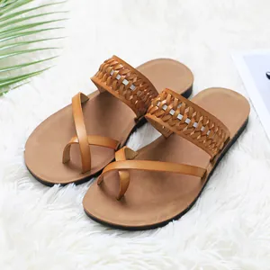 Women's elegant tan flat sandals featuring a woven strap and fashionable cross toe loop design