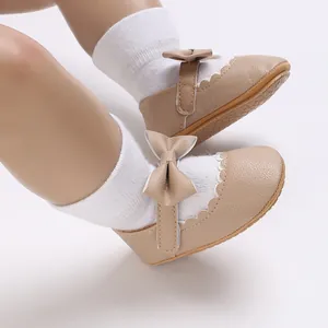 Close-up detail of beige baby girl princess shoes with a cute bow and scalloped edges