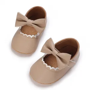 Detailed view of beige baby walking shoes with bow decoration and scalloped edges