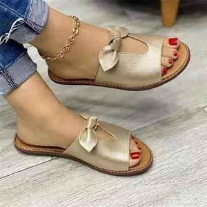 Elegante goldene Sandalen mit Schleife und Ausschnitt-Detail am Fuß des Models.