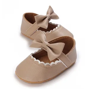 Detail view of khaki baby walker shoes with scalloped edges and bow decoration.
