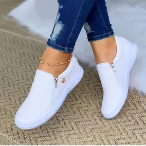 Λευκά γυναικεία casual sneakers με πλαϊνό φερμουάρ και στρογγυλή μύτη πάνω σε χαλί