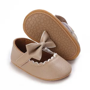 Detail view of khaki faux leather infant shoes with elegant bow and scalloped trim.