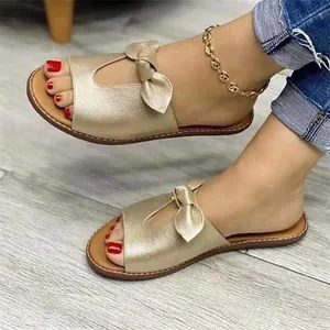 Elegante goldene flache Sandalen mit Schleifendetail und strukturierter Oberfläche.