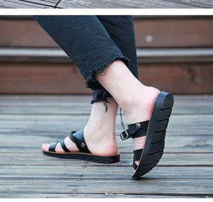 Vue détaillée de sandales plates noires à brides sur un modèle sur une terrasse en bois.