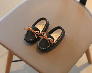 Close-up of toddler loafers with bow detailing on a stylish brown chair