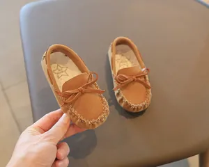Close-up of brown suede children's loafers featuring a bow and white stitching