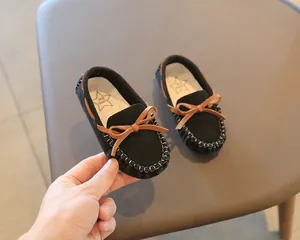 Close-up view of black suede kids' loafer shoes featuring a stylish brown bow knot