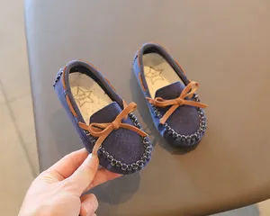 Detailed macro view of navy blue suede toddler loafers featuring a stylish brown bow