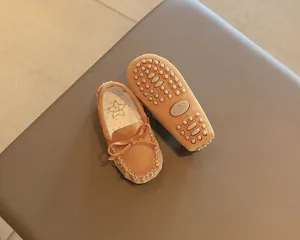 Detailed view of brown toddler loafer shoes showing bow accent and anti-slip pebble sole.