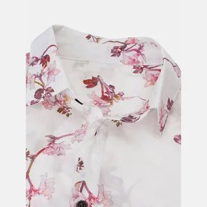 Close-up detail of a white men's Hawaiian shirt with pink floral print and black button.