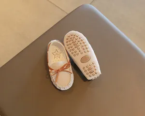 Close-up detail of children's loafers showing non-slip rubber sole and cute bow tie