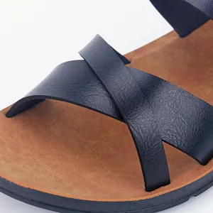 Gros plan de sandales plates pour femmes avec lanières en microfibre noire et semelle beige