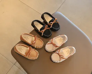 Close-up of children's British style bow-knot loafers in black, camel, and beige colors.