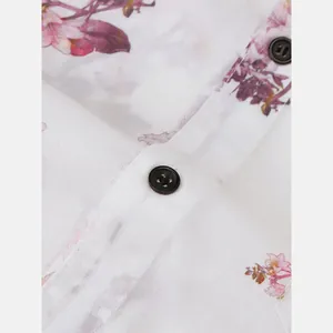 Close-up detail of white floral Hawaiian shirt showing fabric texture and black buttons