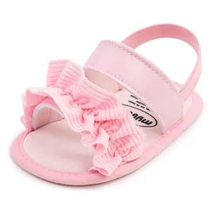 Nahaufnahme von niedlichen rosa Babysandalen mit Rüschenriemen und weicher Lauflerner-Sohle