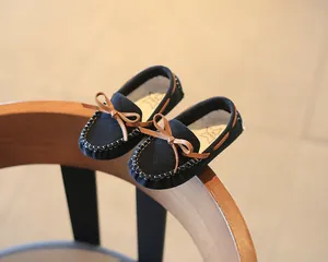 Detailed view of children's black suede loafers featuring a stylish brown leather bow