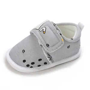 Détail d'une chaussure bébé avec cygne, semelle souple et fermeture velcro.