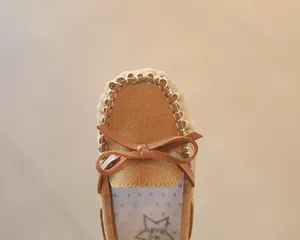 Close-up of brown suede toddler loafers with bow detail and white stitching