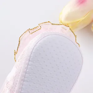 Close-up of pink baby princess shoe with white anti-slip dotted sole and lace detail