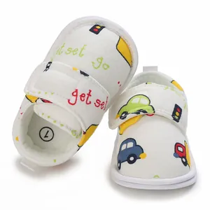 Gros plan sur des chaussures de marche bébé blanches avec motifs voitures et velcro