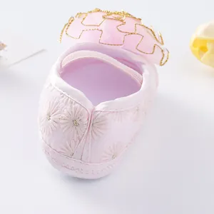 Close-up of pink baby princess shoe with daisy embroidery and gold-trimmed ruffle