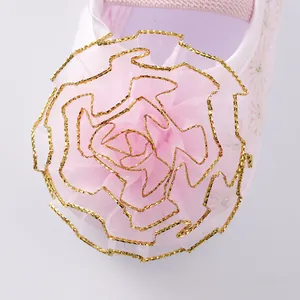 Detailed view of elegant pink mesh flower with gold-trimmed edges on baby princess shoes.