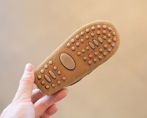 Macro view of toddler moccasin sole featuring brown anti-slip rubber studs and size mark.