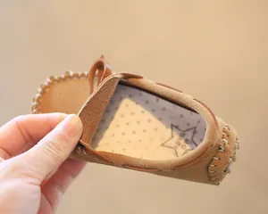 Detailed view of brown suede children's moccasin with a cute star pattern inner lining