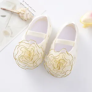 Close-up detail of baby girl princess shoes featuring large cream mesh flower with gold trim