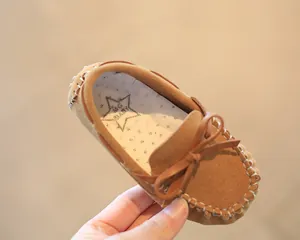 Detail view of stylish children's tan suede moccasins with cute bow-knot and soft insole