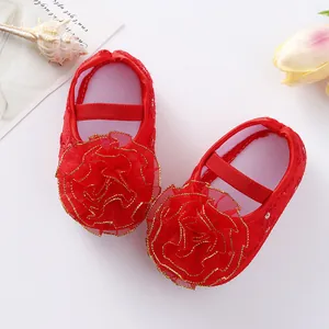 Close-up detail of red baby princess shoes featuring large mesh flowers and gold trim