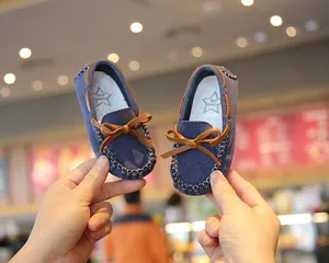 Detailed view of navy blue children's suede loafers with brown leather bow details.