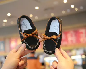 Detail showing black suede toddler moccasins with cute brown bow and star logo insole
