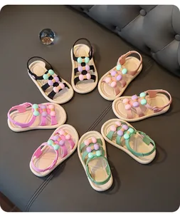 Colorful kids' sandals with cute pastel bows arranged in a circle on a grey background