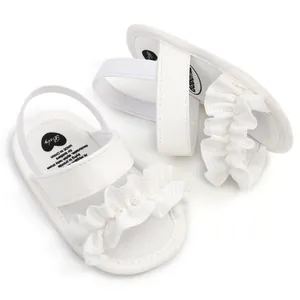 Nahaufnahme weißer Lauflernschuhe für Babys mit elegantem Rüschendesign am Riemen