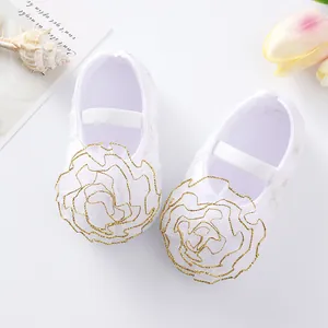 Close-up detail shot of adorable white baby princess shoes with gold-edged mesh flowers