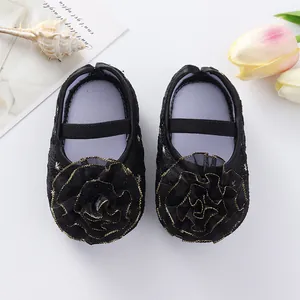 Detailed top view of cute black baby princess shoes with gold-edged fabric flowers.