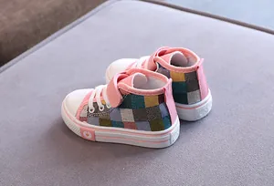 Dettaglio di scarpe in tela alte da bambino rosa con un motivo a quadri colorati