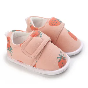 Détail de chaussures de marche pour bébé roses avec motif fraise et bande velcro