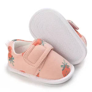 Détail de chaussures bébé roses avec motif fraise et semelle souple antidérapante
