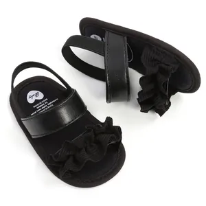 Detailansicht schwarzer Babysandalen für Mädchen mit Rüschen und elastischem Riemen.