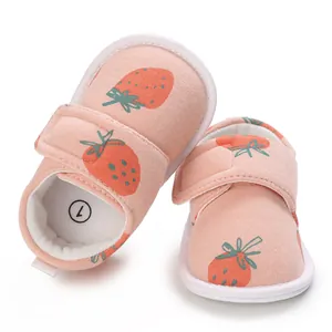 Détail de chaussures bébé roses à motif fraises avec semelles souples.