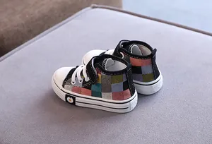 Dettaglio di scarpe di tela alte per bambini con motivo patchwork e decoro a margherita.