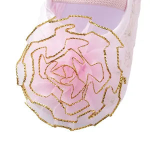 Close-up of a pink baby princess shoe featuring a large mesh flower with gold trim