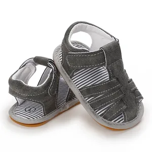Detalle de sandalias de gamuza gris para bebé con suela de goma suave y rayas blancas