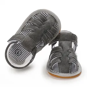 Primer plano de sandalias grises para bebé con suelas blandas y forro de rayas.