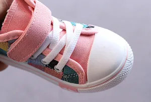 Primo piano di scarpe in tela rosa per bambini con cinturino in velcro e punta.