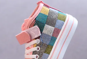 Dettaglio del motivo a scacchi colorati e del velcro sulle scarpe di tela alte per bambini.