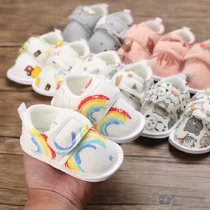 Détail d'une chaussure de marche souple pour bébé avec motif arc-en-ciel en main
